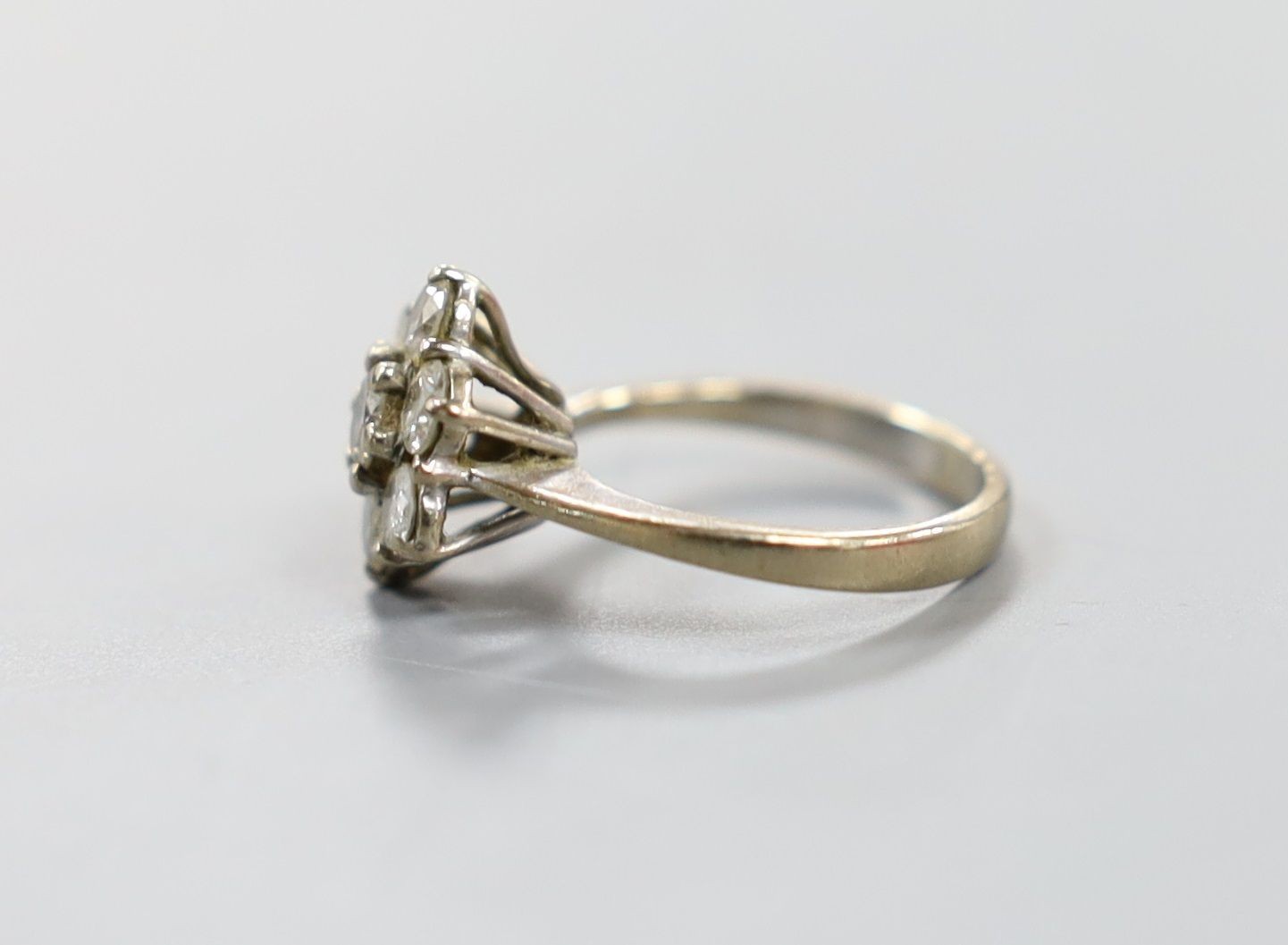 An 18ct and seven stone diamond set flower head cluster ring, size F/G, gross weight 3.2 grams.
